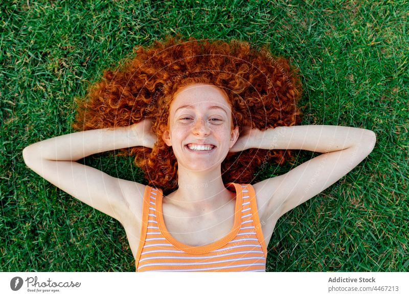 Cheerful woman with hands behind head lying on grass happy relax individuality lawn chill enjoy delight pleasure female cheerful appearance glad optimist