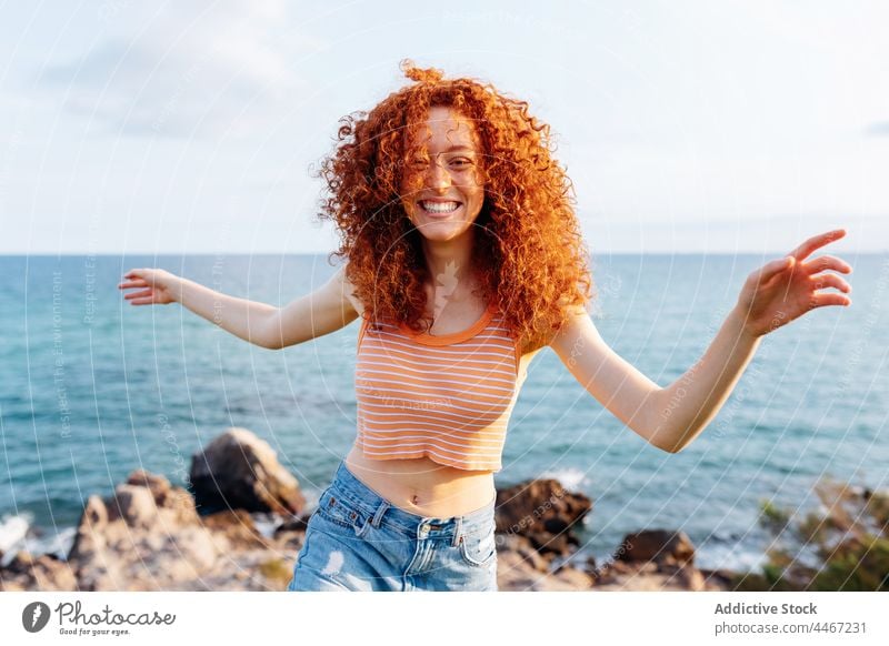 Carefree woman dancing on hill in seashore dance enjoy move energy coast freedom happy expressive female smile outstretched arms run nature travel flying hair