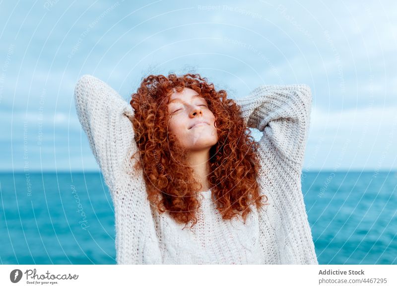 Cheerful woman with hand behind head on seashore happy relax pleasure expressive freedom personality individuality enjoy female cheerful portrait carefree