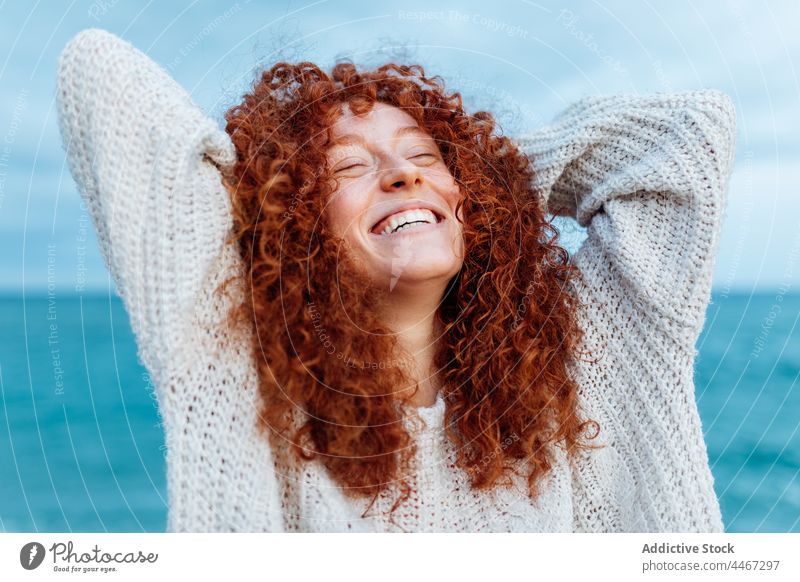 Cheerful woman with hand behind head on seashore happy relax pleasure expressive freedom personality individuality enjoy female cheerful portrait carefree