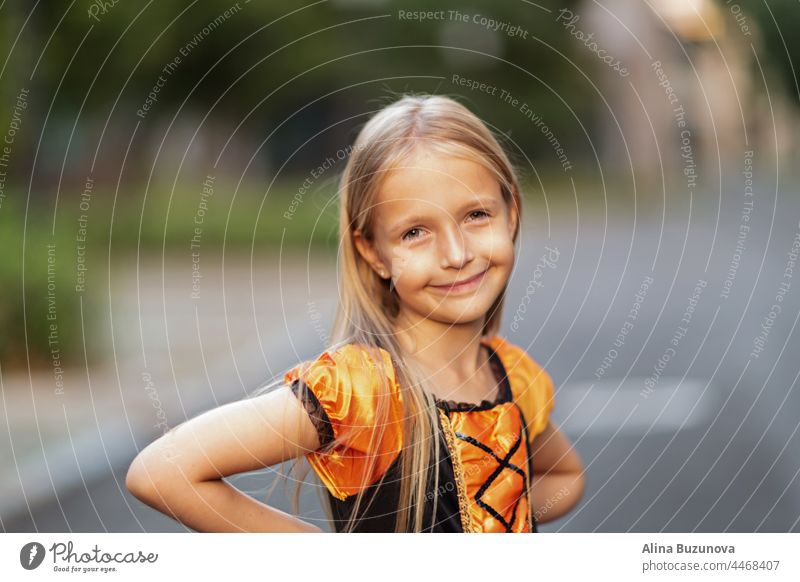 Little Caucasian Girl in costume of which orange and black color and celebrating Halloween outdoor halloween witch hat child girl celebrate Scary kid person