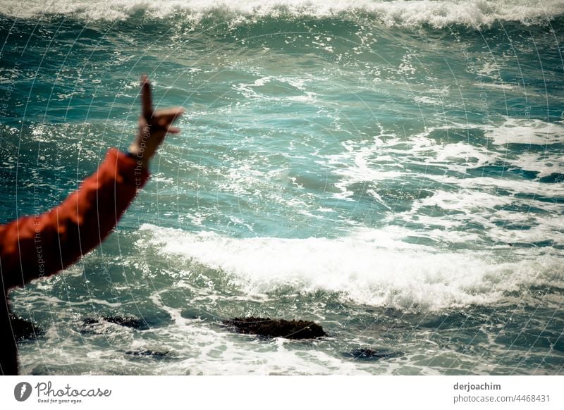 constructive / The raised hand with the red sleeve stands at the foaming sea and warns the swimmers at the beach of the not visible undercurrent. Seashore