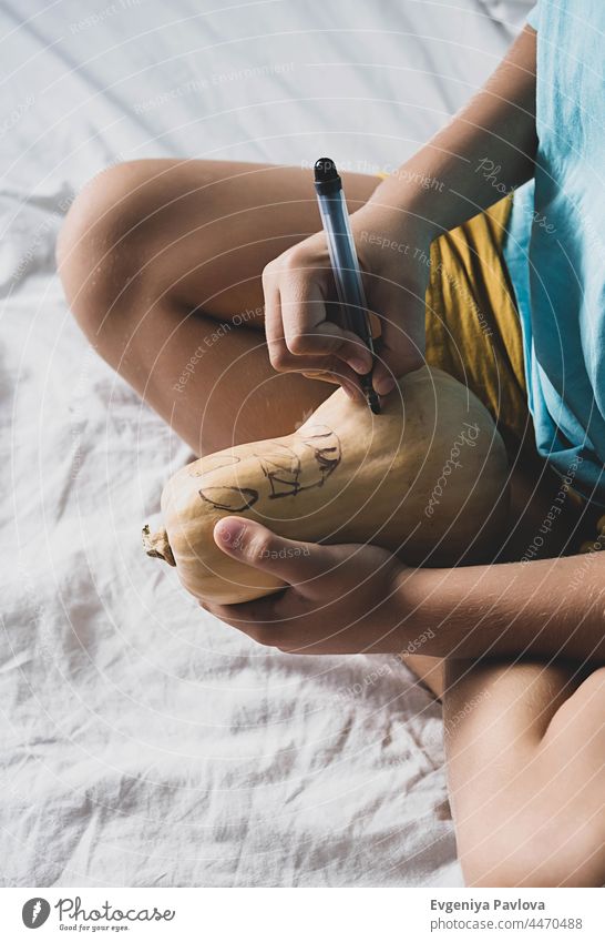 Boy making Jack-o-Lantern at home. Halloween DIY concept. boy pumpkins decor diy child paint felt-tip pen lifestyle fall art festive drawing kid funny homemade