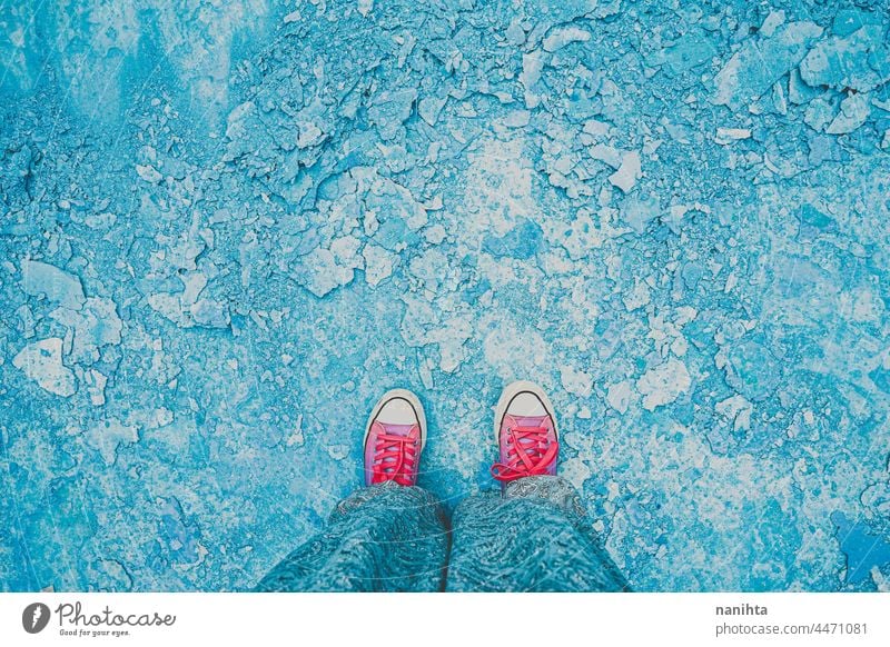 High angle view of a young woman legs in an empty pool feet blue pink background abstract high perspective sneakers opposites cool cold tones trendy texture