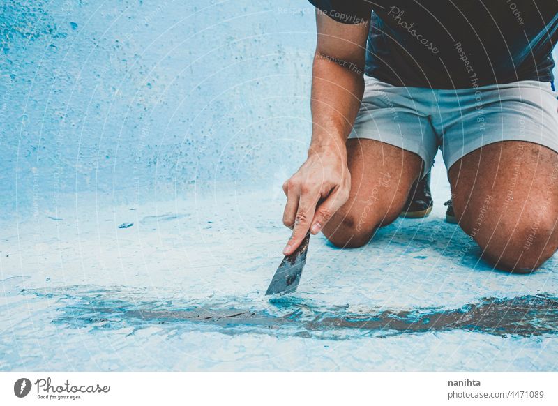 Close up of a man fixing the floor of a pool maintenance crack diy putty putty knife palette palette knife work job home craft hard hard work physical strong