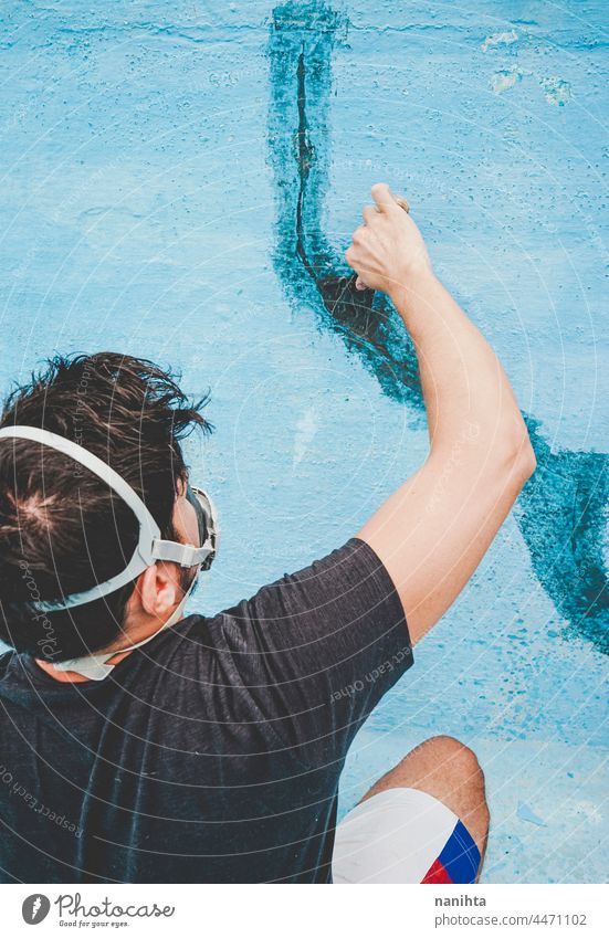 Young man working in his swimming pool maintenance diy mask putty putty knife putty palette blue turquoise job tools hard physical composition paint fix fixing