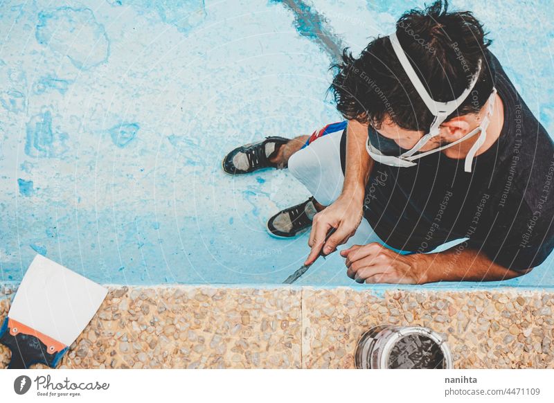 Young man working in his swimming pool maintenance diy mask putty putty knife putty palette blue turquoise job tools hard physical composition paint fix fixing