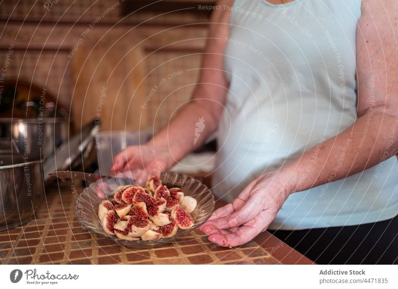 Crop old woman with fresh fig slices in kitchen fruit natural culinary vitamin ripe sweet home fiber organic peeled recipe fragrant piece pulp scent house