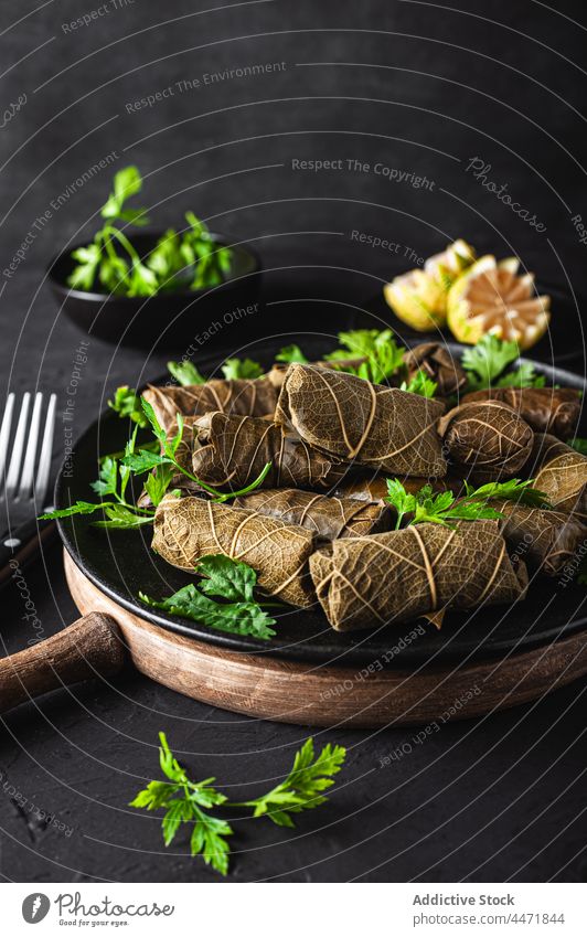 Plate with delicious sarma dish with parsley and lemon fork knife palatable dolma meat grape leaves tasty cuisine ingredient citrus dinner meal fresh