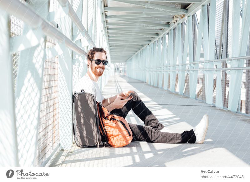 Urban young man talking on smart phone traveling inside in airport. Casual young businessman wearing suit jacket. Handsome male model. Young man with cellphone at the airport while waiting for