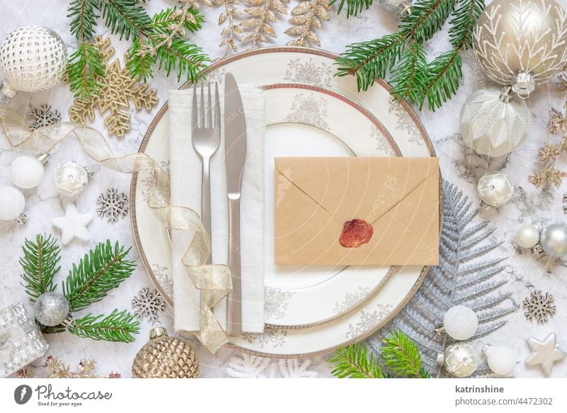 Festive table setting of with fir tree branches and Christmas decorations. Envelope mockup christmas ornaments holiday new year white marble silver golden