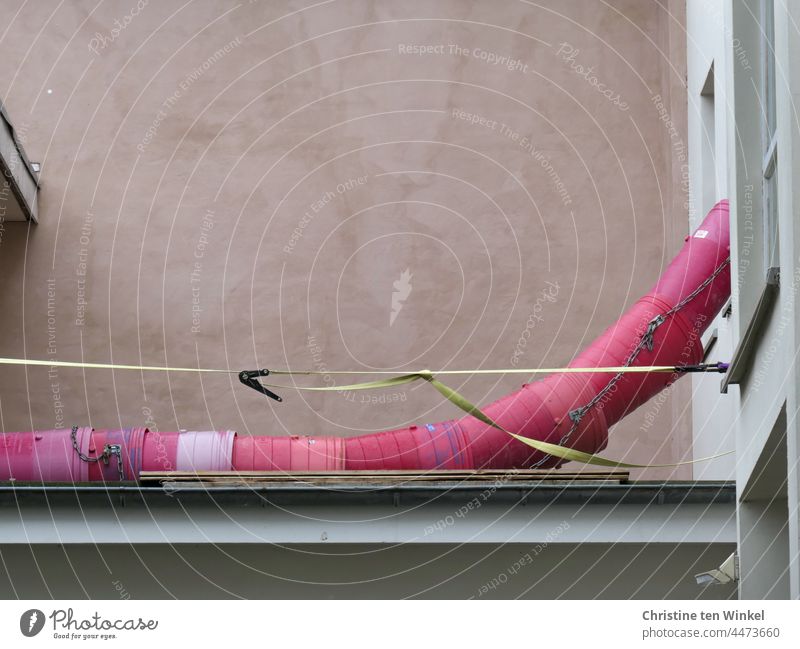 constructive | renovation of an apartment. A pink rubble slide hangs out of a window and lies on the adjacent flat roof rubble chute pink rubble chute