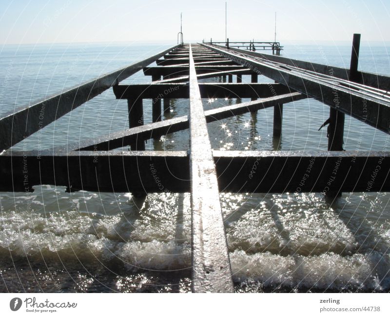 jetty Ocean Jetty Railroad tracks Glittering reflection Sun Water old metal