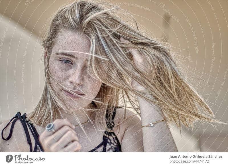 Young blonde woman with freckled face and hair blowing in the wind pretty green eyes lifestyle people attractive young woman girl adult person white blond hair