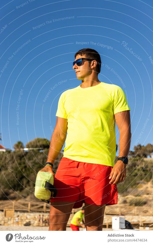 Lifeguard observing sea on sandy beach man lifeguard safety observe duty protect work male water shorts seashore lifesaver seaside wave nature seacoast clear