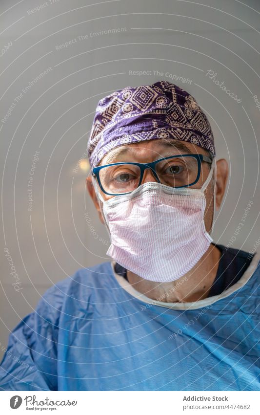 Senior doctor in surgical suit and mask in clinic man surgeon medicine old professional operation portrait occupation treat male hospital surgery hat