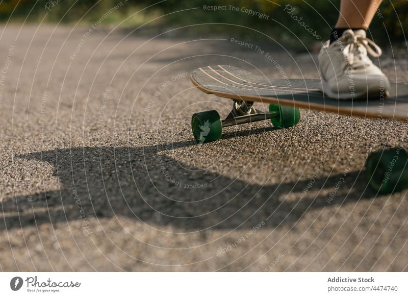 Anonymous woman riding longboard on asphalt road ride activity hobby enjoy leisure nature balance female cloudy training hill carefree active practice energy