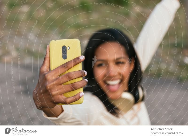 Ethnic woman on longboard taking selfie on smartphone fun using delight hobby female happy toothy smile leisure show optimist activity device ethnic