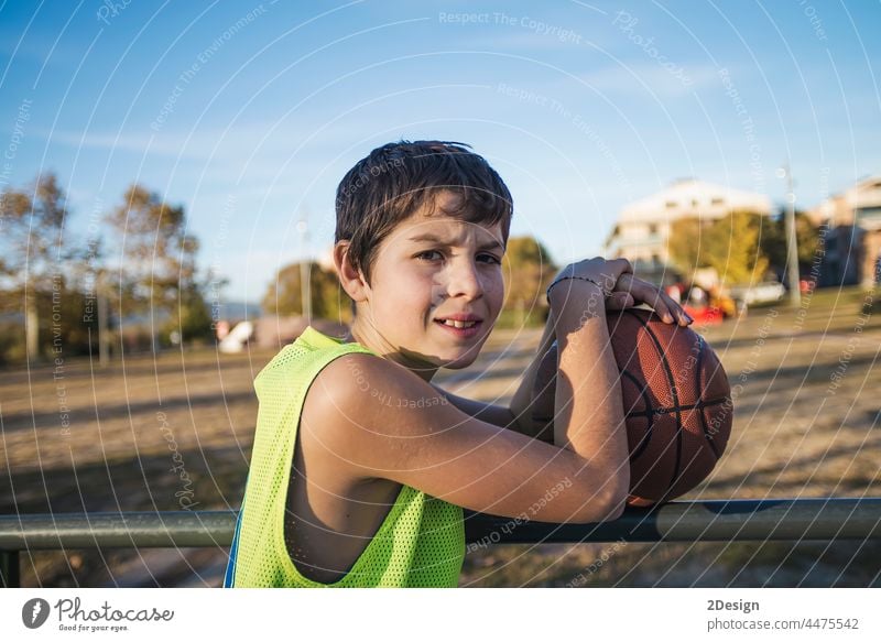 Young teen male with sleeveless standing on a street basket court while smiling at camera basketball player real teenage youth boy fit happy game people active