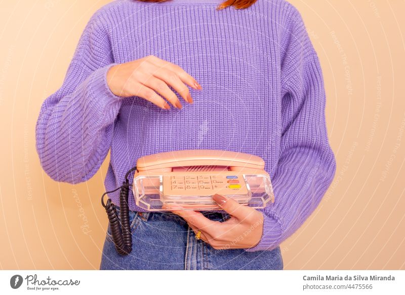 Woman in lilac sweater, jeans and socks holding a phone. Beige background. beige business call casual classic communication fashion fun girl hand lifestyle