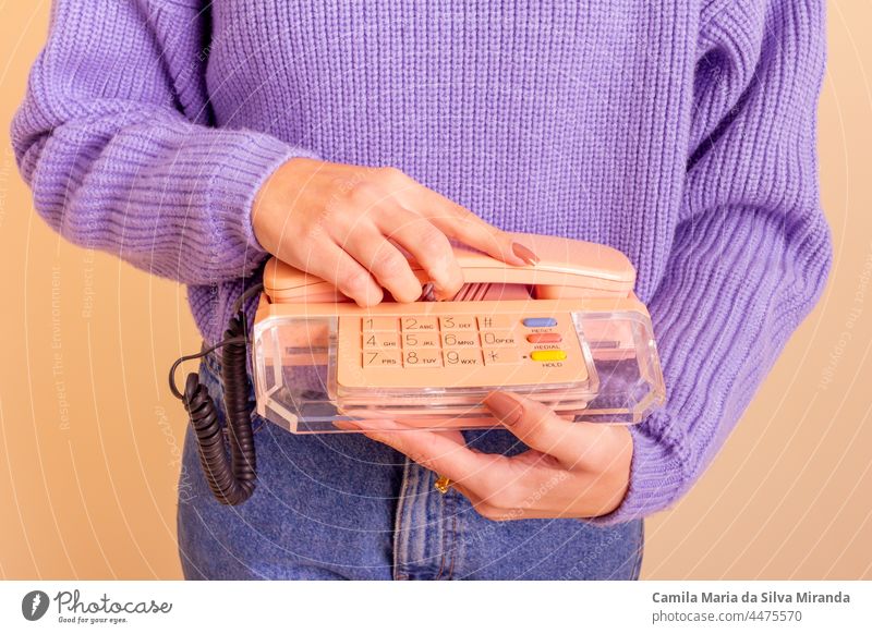 Woman in lilac sweater, jeans and socks holding a phone. Beige background. beige business call casual classic communication fashion fun girl hand lifestyle