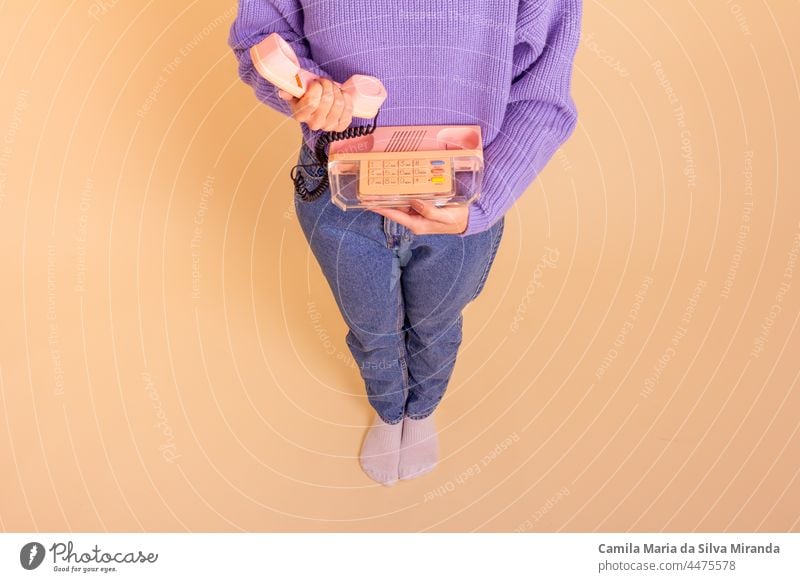 Woman in lilac sweater, jeans and socks holding a phone. Beige background. beige business call casual classic communication fashion fun girl hand lifestyle