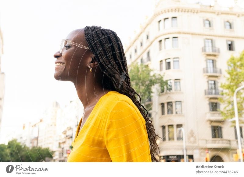 Cheerful black woman on street urban city building district leisure appearance neighborhood style female positive african american cheerful smile happy glad