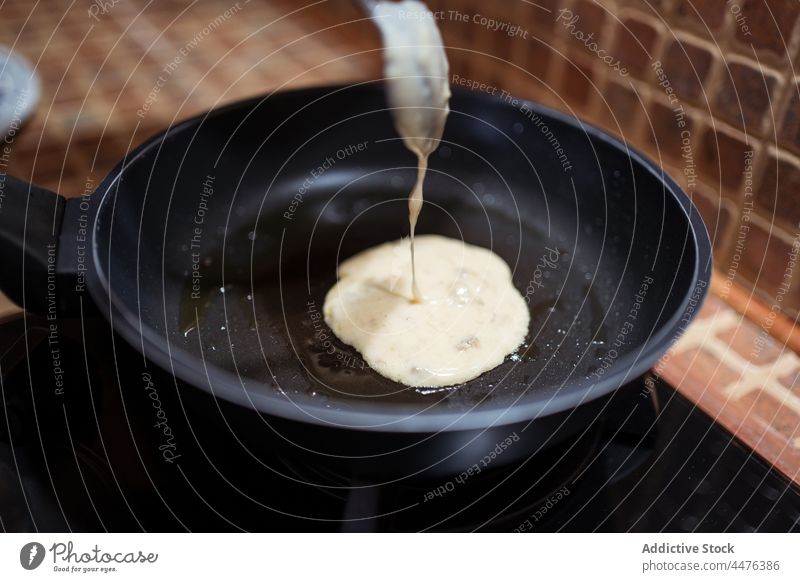 Crop woman frying pancakes in pan stove kitchen cook process delicious food home female prepare homemade recipe bowl glass spoon pour yummy tasty ingredient