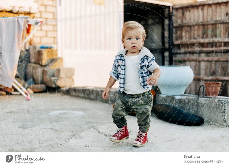 A charming little boy is walking in the backyard of a farm barn background little farmer kid baby building outdoors cute white young child family summer nature