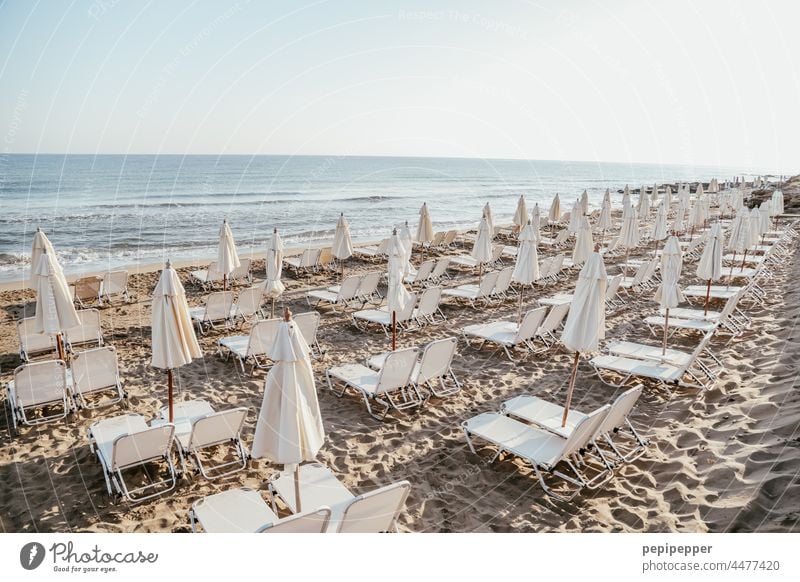 empty beach with folded umbrellas and empty sun beds Beach sunshine Sunshade parasols Sun loungers Couch Deckchair Vacation & Travel Ocean Summer Relaxation