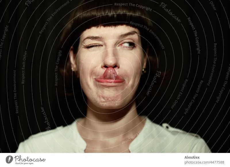 NAhes portrait of a young woman touching the tip of her nose with her tongue and blinking to the side Woman Young woman pretty Slim green-eyed Intensive hands