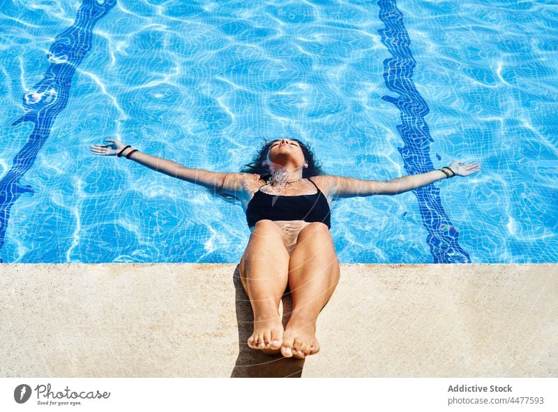 Attractive woman in swimsuit in pool water bikini summer resort vacation sunlight poolside charming young hispanic ethnic female holiday aqua rest swimwear