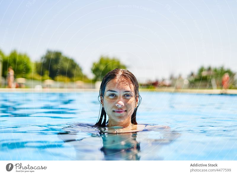 Young woman in swimming pool water summer happy resort vacation smile wet hair female weekend joy clean glad holiday pleasure poolside swimwear aqua positive