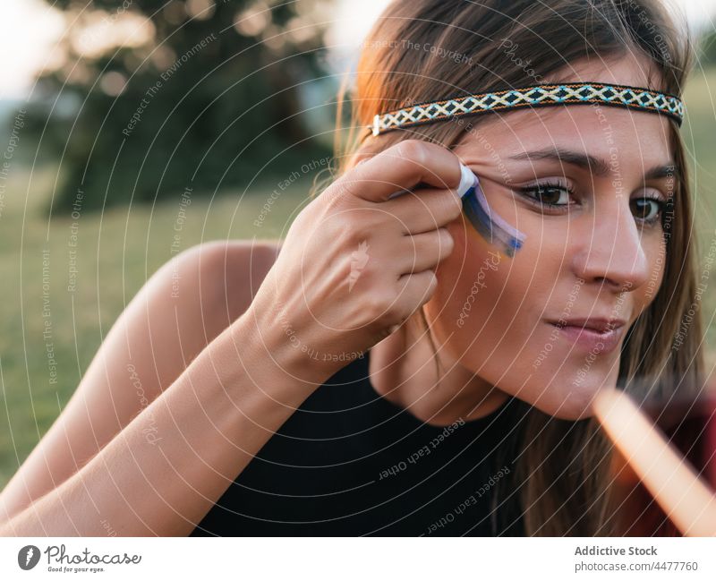 Woman painting rainbow on face with a stick hippie liberty lgtbi lgtbiq freedom lifestyles peace purple love magenta people retro lesbian color image colorful