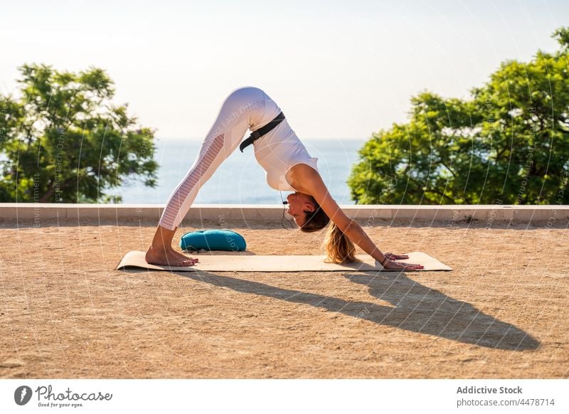 Lady doing Adho Mukha Shvanasana woman downward facing dog adho mukha shvanasana yoga exercise position practice pose flexible wellness mat barefoot peaceful