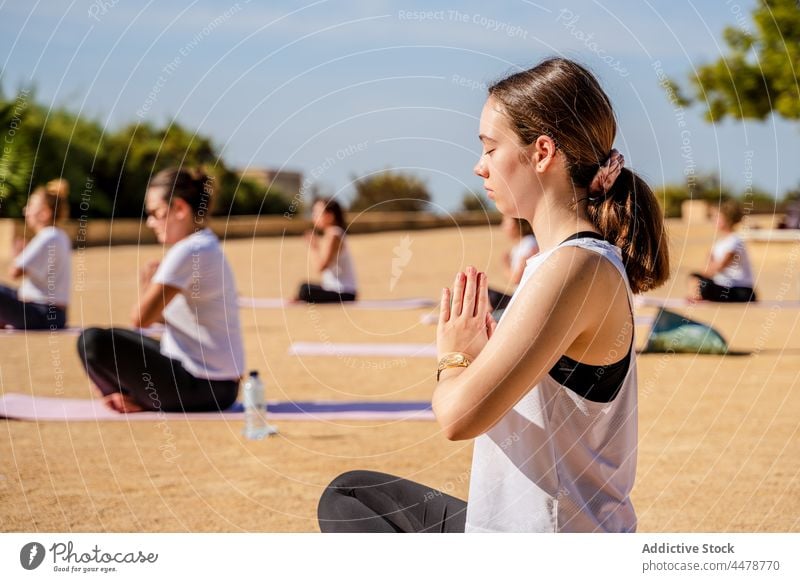 Female sitting in lotus pose with Namaste hands during yoga practice woman calm namaste padmasana wellness activewear female young barefoot mat eyeglasses