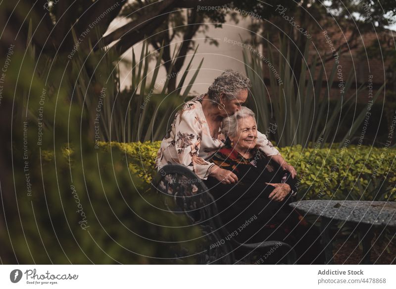 Senior woman kissing sister on head women garden happy hug love tender together weekend female elderly aged senior smile embrace park relationship cheerful joy