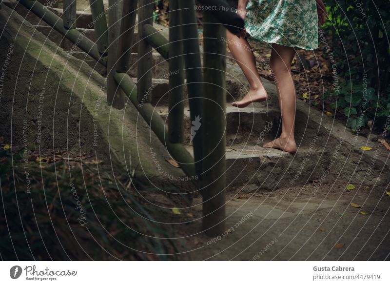 Bare feet climb stone stairs and wooden railing. Barefoot ladders Walking Exterior shot Colour photo conceptual Feet