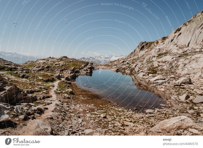 Mountain lake on the Grimsel Pass Switzerland Nature Hiking Tourism Alps hike Beautiful weather Summer Blue sky Rock mountain lake Trip Vacation & Travel