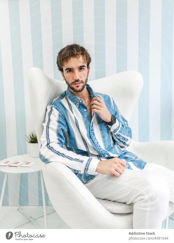 Stylish man sitting on armchair well dressed elegant confident beard charismatic style apparel collar adjust male trendy serious appearance handsome outfit guy