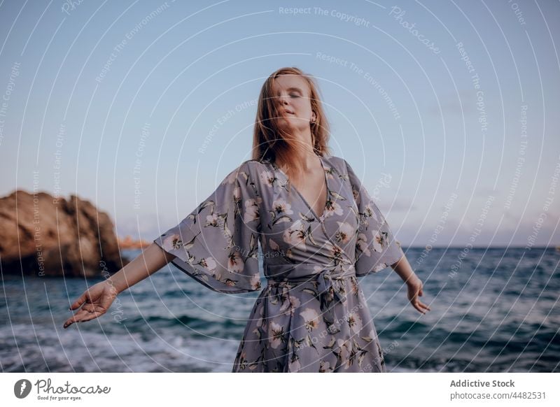 Woman in stylish dress standing on seashore woman summer evening beach trendy sunset sundown sky female delight happy style coast joy water rock seaside glad