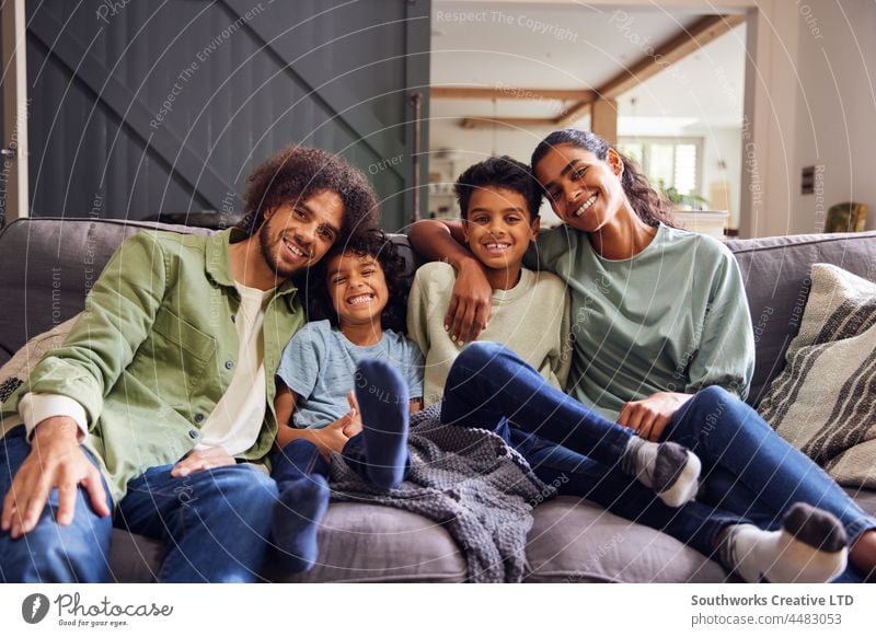 Portrait of happy family on sofa mixed race asian portrait weekend relax love together indoors day home interior four people authentic childhood leisure parent