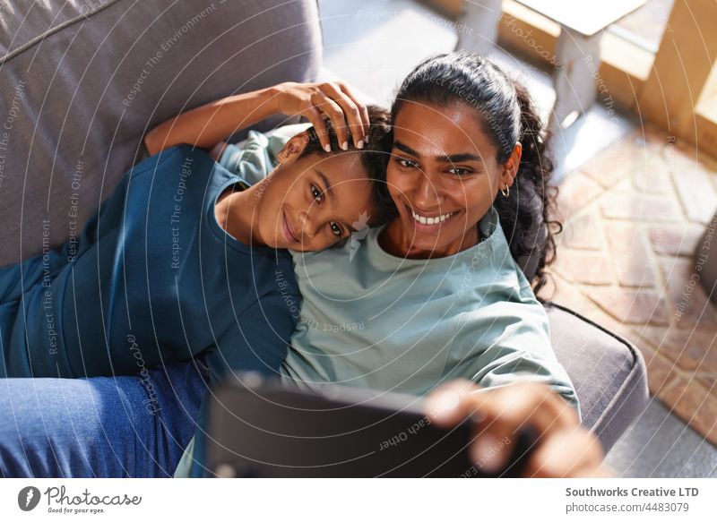 Mother and son taking selfie on phone mixed race asian mother relax leisure bonding love indoors day home interior two people portrait authentic childhood