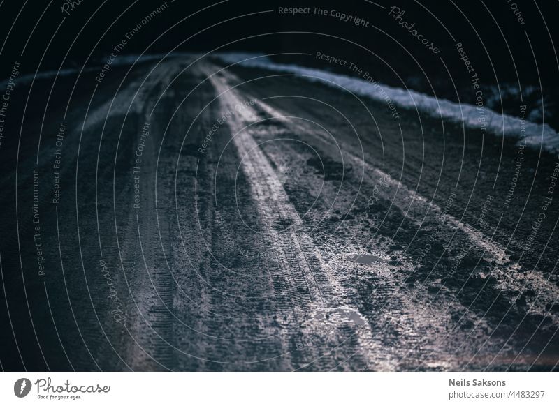 Mud, ice, snow on the road in the countryside close-up. Close up of footprints and tires on the road in winter. Transport and safety. abstract asphalt