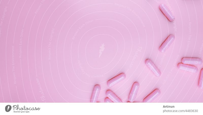 Top view pink capsules pill on pink background. health care web banner. vitamins and supplements for women concept. pharmaceutical industry. breast cancer or woman health topics. healthy living.