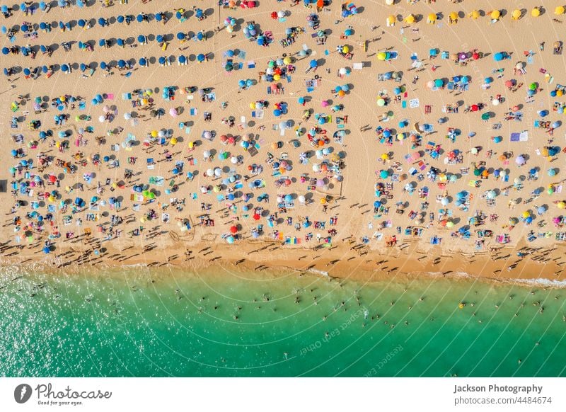 Drone shot of many people enjoying the beach and the ocean in high season- vacation pattern. crowded overcrowded texture umbrella tourists destination turquoise