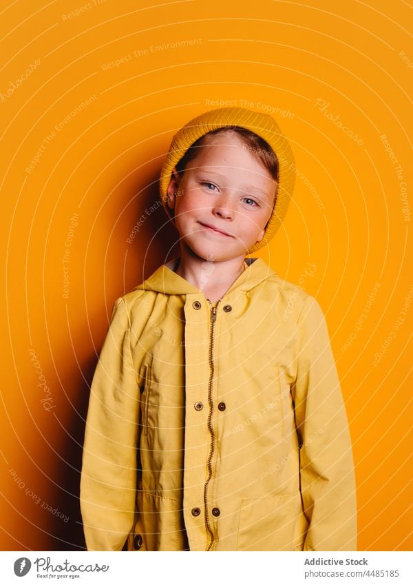 Laughing boy looking at camera against yellow background happy laugh cheerful autumn portrait jacket outerwear beanie glad joy style kid trendy child bright