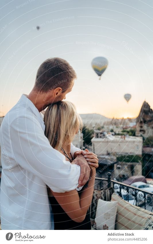 Husband looking away while hugging wife on terrace couple embrace soulmate admire together rooftop date romantic air balloon love relationship bonding weekend