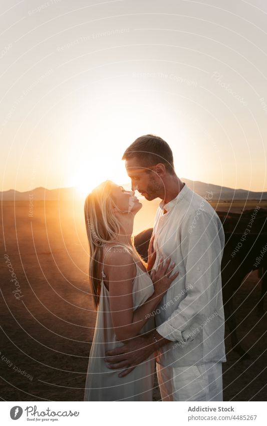 Guy hugging wife near horses on pasture couple countryside field embrace eyes closed relationship affection animal together love hill nature boyfriend idyllic