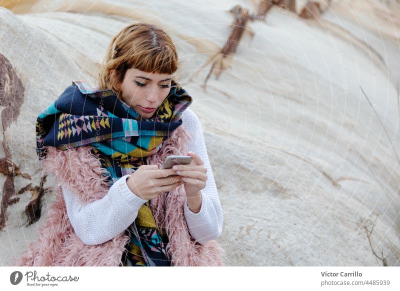 A young blonde woman with a cell phone in a beach in winter childhood fun baby people snow kid happiness mother hat beauty smile smiling boy person scarf cold